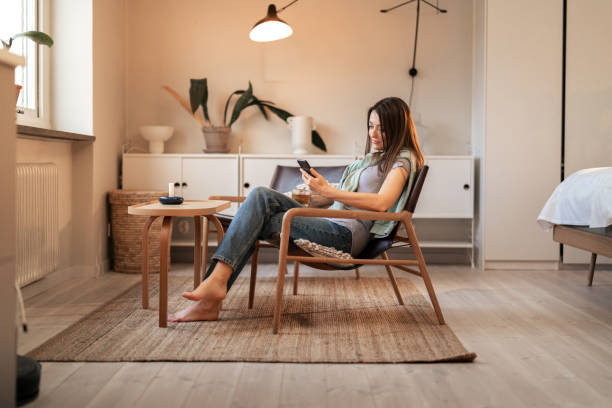 istock Woman relaxing in modern home using smartphone with hot tea 2198748481