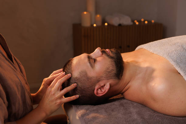 istock Relaxed man enjoying a head massage in a serene spa setting with calming candlelight ambiance and peaceful atmosphere. 2198748660