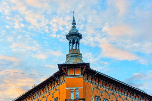 Budapest, Hungary - November 24, 2024: Captivating view of an ornate building with a spire in Budapest, highlighting the rich architectural detail against a vibrant sunset sky.