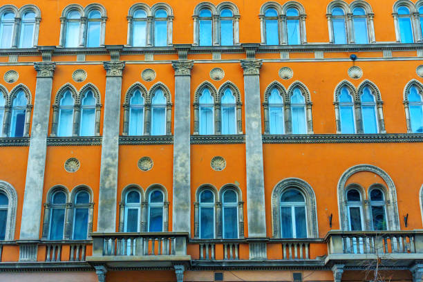Budapest, Hungary - November 24, 2024: Intricate details of an orange building facade featuring arched windows and decorative elements, highlighting architectural beauty in Budapest.