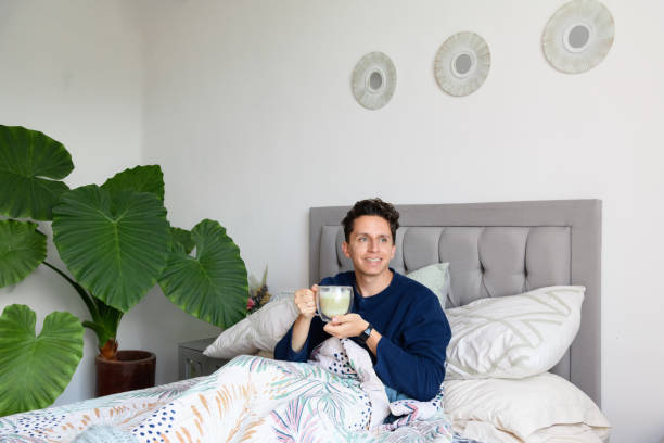istock Man waking up in a bed while drinking coffee and is happy in a bedroom 2198749154