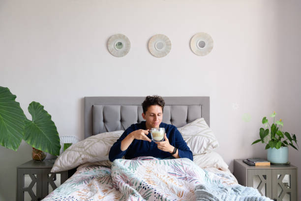 istock Man waking up in a bed while drinking coffee and is happy in a bedroom 2198749957