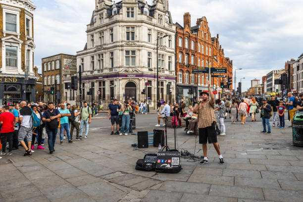 A talented street musician performs in Camden Town, London, as a crowd gathers in the lively urban setting, capturing the essence of street culture and live entertainment. London, UK, 8 July 2023