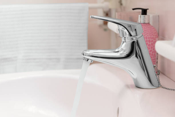 istock Sink faucet with water stream and some blurred accessories in a bathroom. 2198751424