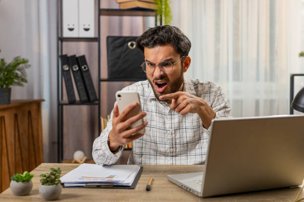istock Furious annoyed angry businessman freelancer engage in heated phone quarrel conversations at office 2198751599