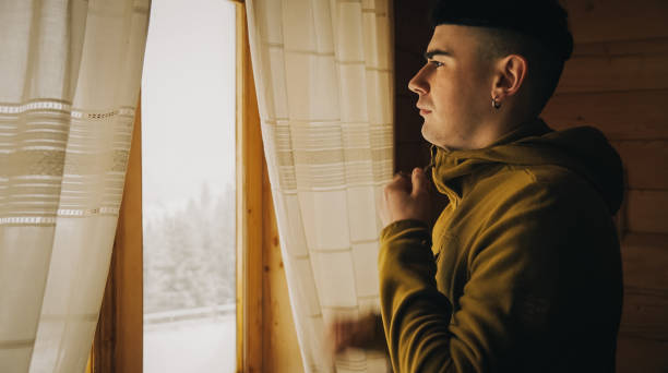 istock Young man looks out window of cottage 2198753015