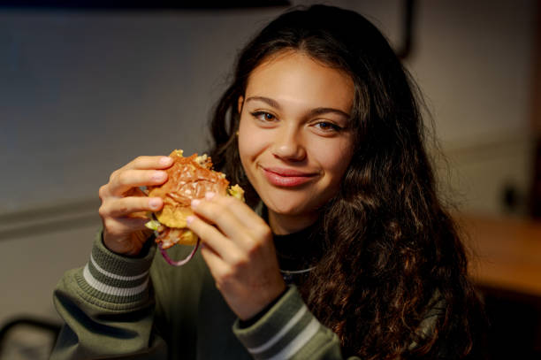 istock Young woman enjoying a delicious hamburger in a restaurant 2198759219
