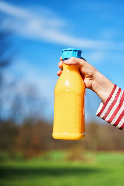 Drinking Orange Juice from Recycled PET Plastic Bottle Outside