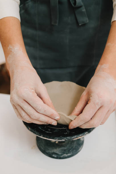 istock Hands shaping clay into dish in the craft studio close-up. Artisan sculpts ceramic bowl using potter's wheel. 2198760946