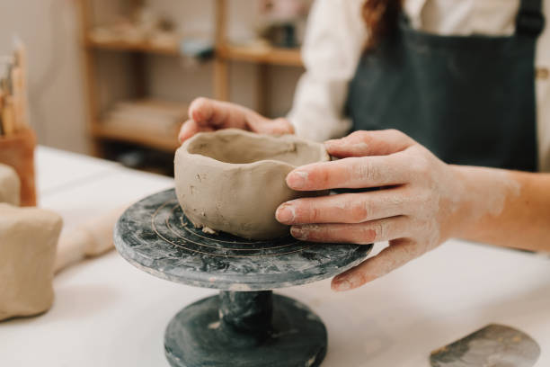 istock Process of creating ceramic products. Female potter hands shows ceramic bowl ready for firing in a kiln. 2198761131