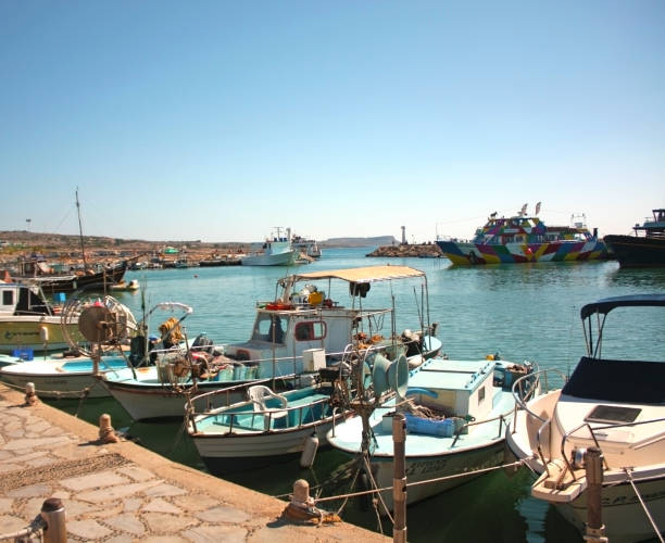 A bustling harbor with boats docked, under a clear blue sky and calm waters.