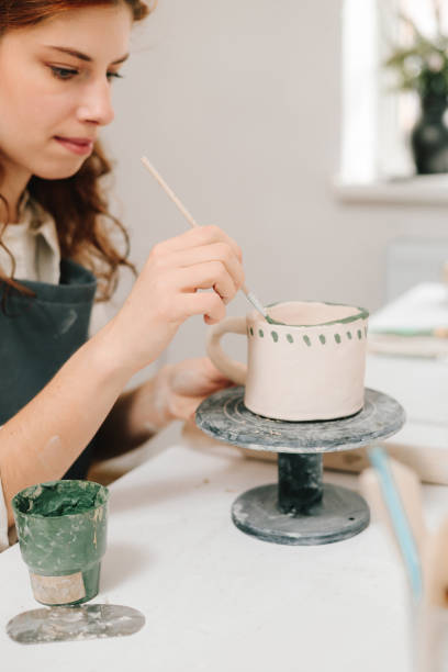 istock Painter is drawing and adding unique designs to the earthenware. Artist is decorating and painting handmade ceramic clay cup in the creative workshop. 2198761677