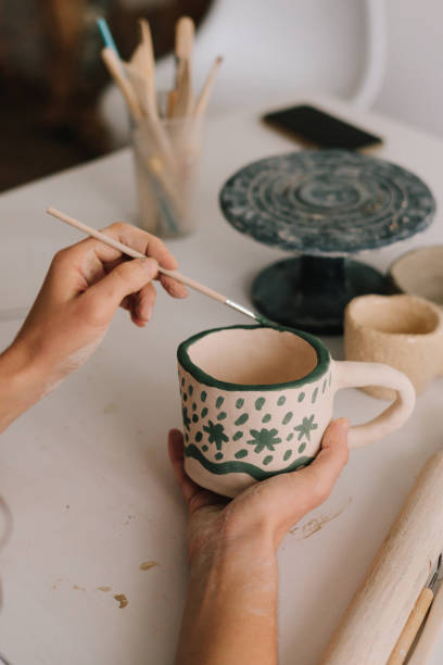 istock Design earthenware cup with a traditional pattern. Artist is making decoration on the clay ceramic mug after oven firing. 2198762072