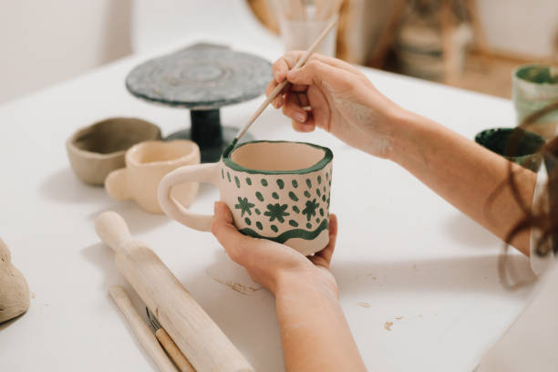 istock Design earthenware cup with a traditional pattern. Artist is making decoration on the clay ceramic mug after oven firing. 2198762922