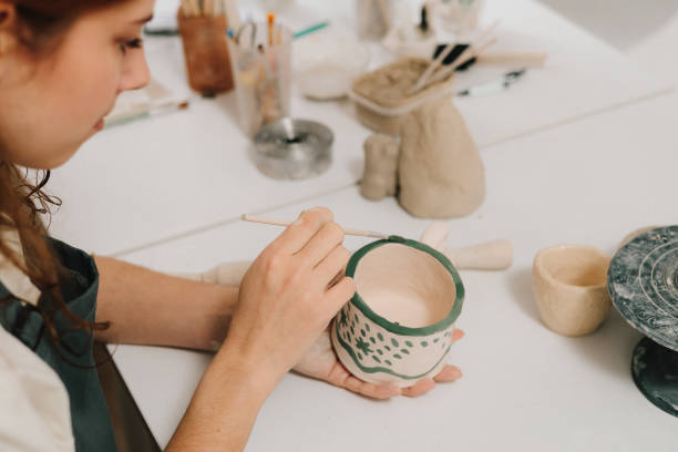 istock Design earthenware cup with a traditional pattern. Artist is making decoration on the clay ceramic mug after oven firing. 2198762975