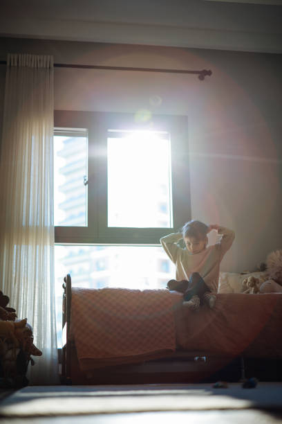 istock Happy funny child girl jumping on bed alone feeling joy 2198764484