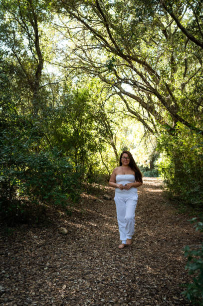 Woman enjoying a serene walk through a sunlit forest, connecting with nature and embracing a sense of freedom and tranquility