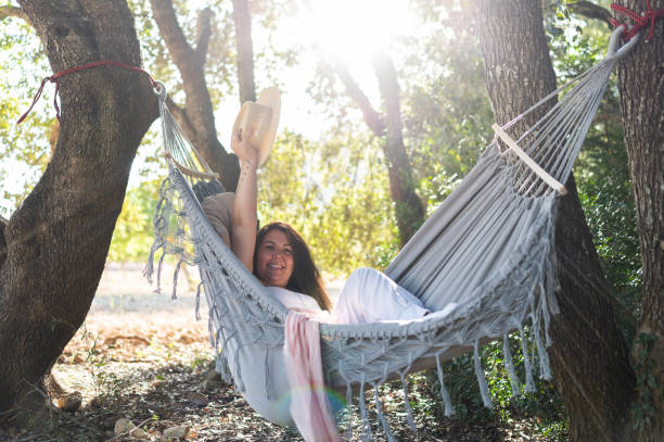 istock Happy woman relaxing in hammock in sunny forest 2198766227