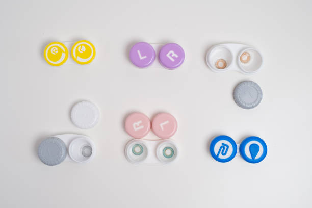 Contact lenses, case and bottle with solution and eye drops on white background. Eye health and care, vision, ophthalmology concept, close-up