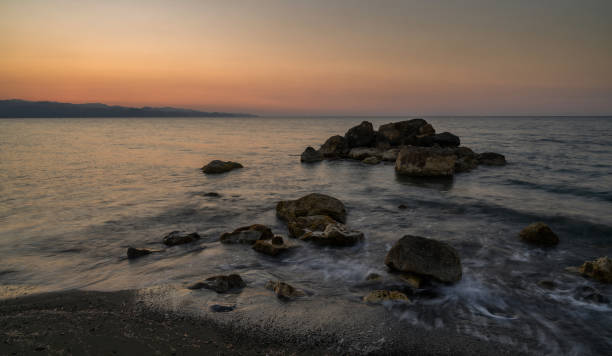 istock Serene twilight over shimmering waves and rocky shoreline by the tranquil sea 2198771973