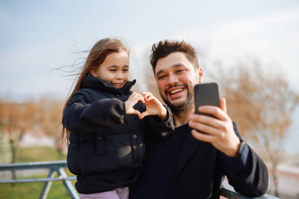 istock Happy father and daughter taking selfie at coastline 2198773495
