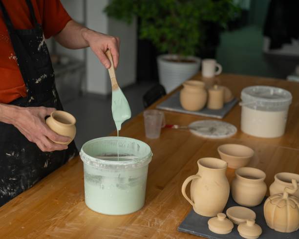 istock Close-up of a potter's hands glazing a pottery piece. 2198775281