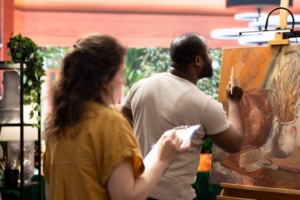 istock Woman master painter teaching her apprentice to use new painting techniques 2198776000