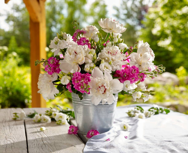 A bouquet of flowers with peonies and wildflowers, set on a garden table.
