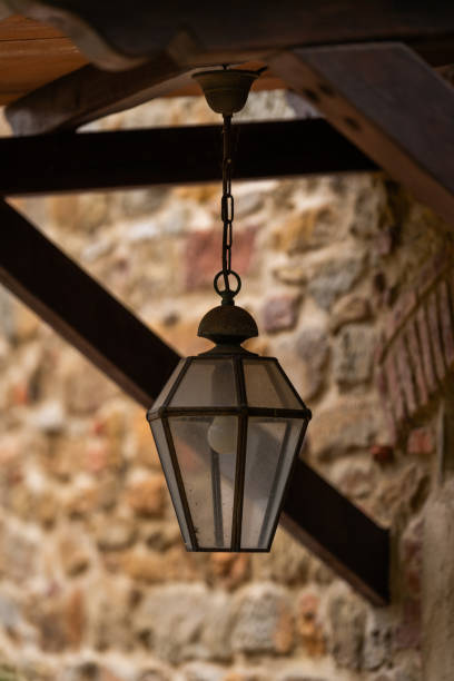 Hanging lantern under wooden beams with stone wall background
