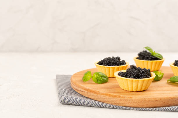 istock Tartlets with black caviar served on on wooden table 2198781717