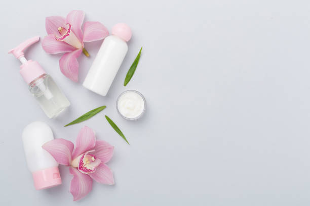 istock Bottles and jars with cream and orchids on color background, top view 2198782732