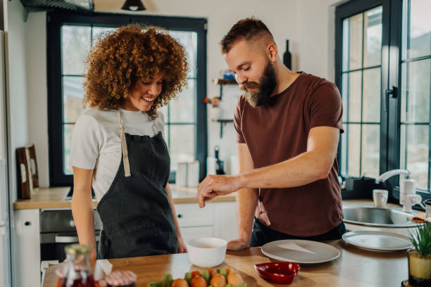 istock Couple cooking together in modern kitchen, adding ingredients to bowl 2198785715