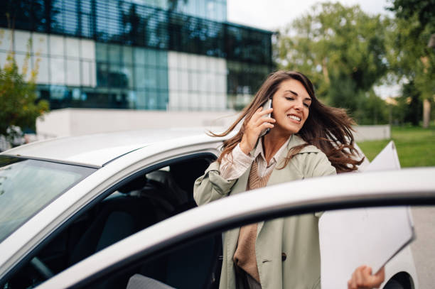 istock Businesswoman talking on phone exiting car with documents 2198786249