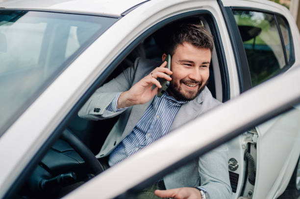 istock Businessman smiling while talking on the phone in his car 2198786265