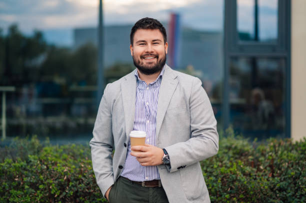 Businessman holding disposable coffee cup outside office building