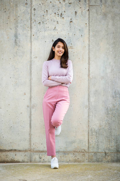 istock Full length smiling woman leaning against wall 2198786673