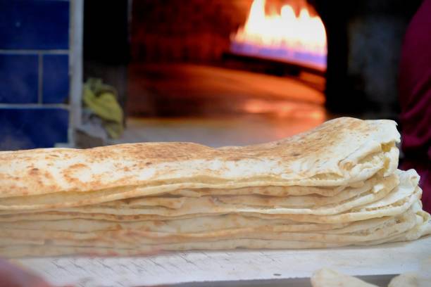 istock Making Ramadan pita on wood fire in a stone oven 2198795134