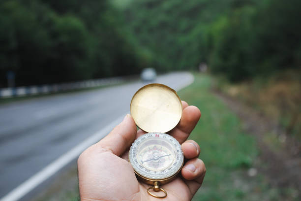 istock a compass in a hand and a road in the background 2198798519