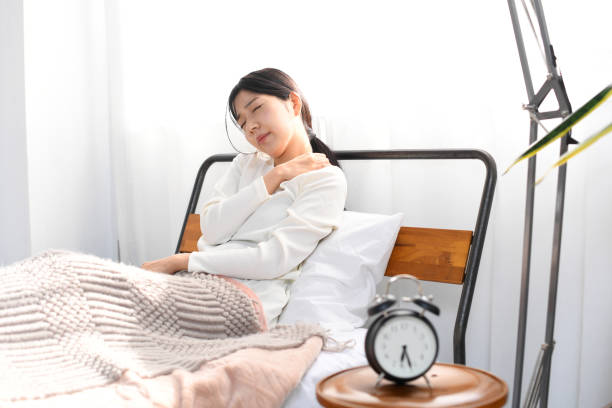 tired asian young woman suffering from stiff shoulders in bed - 不眠症 日本人 ストックフォトと画像
