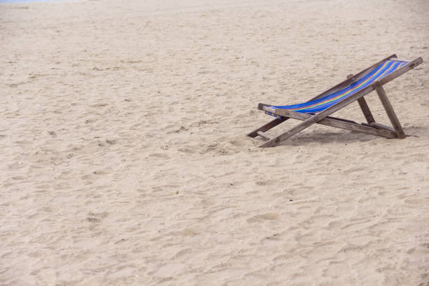 Relaxing blue and white striped beach chair on a sandy beach. Solitude on a tranquil beach.