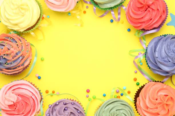 istock Delicious cupcakes with bright cream and party decor on yellow background, flat lay. Space for text 2198805331