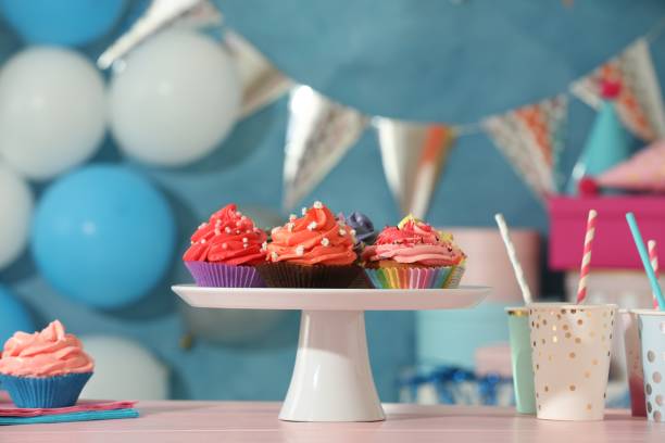 istock Different colorful cupcakes and party accessories on pink table 2198805345