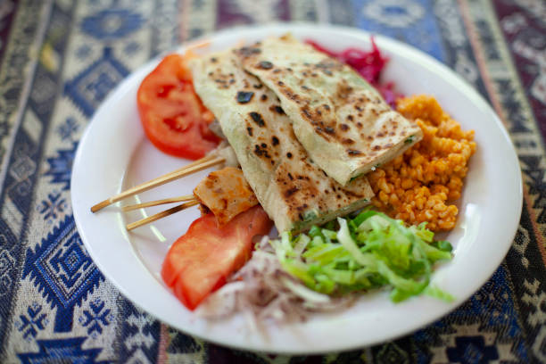 Dinner plate with Gozleme savoury traditional Turkish pastry dish, made of hand-rolled dough that is lightly brushed with butter and eggs, filled with various toppings, served with salad and meat on skewers