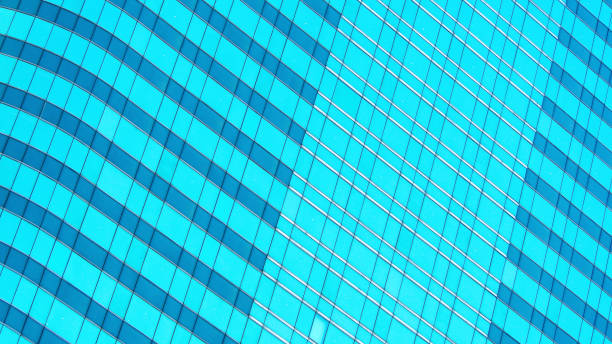 istock a striking blue glass facade with a wavy, grid-like pattern. The alternating light and shadow create a dynamic and rhythmic effect, highlighting the building's architectural flow. 2198806683