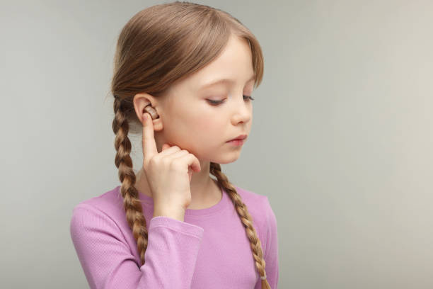 istock Little girl with hearing aid on grey background. Space for text 2198807774