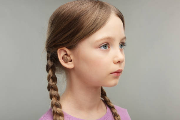 istock Little girl with hearing aid on grey background 2198808088