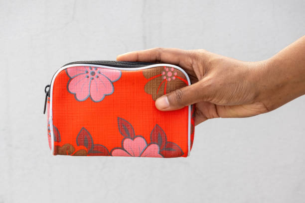 istock A woman's hand holds a small, red purse adorned with a floral pattern. This purse, typically made of leather, plastic, or fabric, is designed for women to carry their money. 2198810539