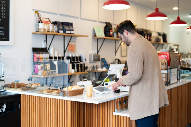 istock Young man making a payment in a local business using cellphone 2198811097