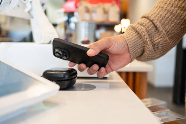 istock Young man making a payment in a local business using cellphone 2198811099
