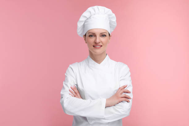 istock Happy woman chef in uniform on pink background 2198812516